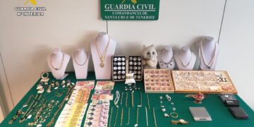 Joyas robadas y efectivo recuperados por la policía, colocados sobre una tela verde.