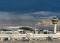 La torre de control de tráfico aéreo y el exterior del aeropuerto de Munich bajo un cielo oscuro y nublado.