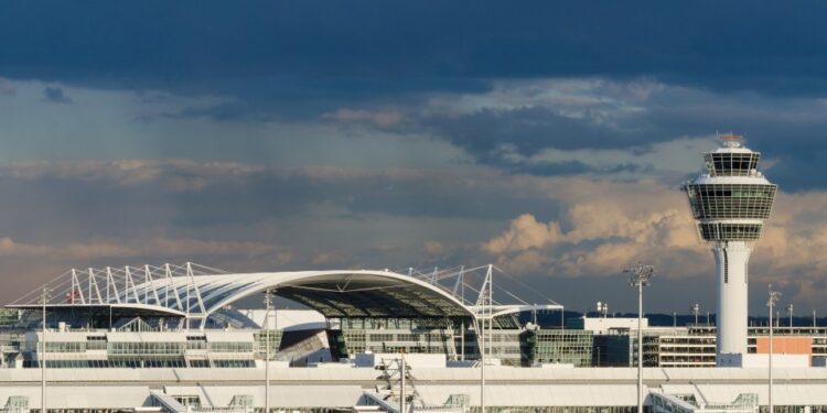 La torre de control de tráfico aéreo y el exterior del aeropuerto de Munich bajo un cielo oscuro y nublado.