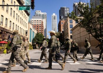 Agentes federales del Servicio de Inmigración y Control de Aduanas de EE. UU. y de Aduanas y Protección Fronteriza de EE. UU. caminan hacia el norte por North Clark Street en el vecindario River North en Chicago el 28 de septiembre de 2025. (Ashlee Rezin/Chicago Sun-Times vía AP)