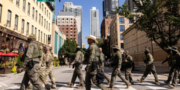 Agentes federales del Servicio de Inmigración y Control de Aduanas de EE. UU. y de Aduanas y Protección Fronteriza de EE. UU. caminan hacia el norte por North Clark Street en el vecindario River North en Chicago el 28 de septiembre de 2025. (Ashlee Rezin/Chicago Sun-Times vía AP)