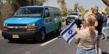 Los israelíes se reúnen con banderas nacionales afuera de la base militar de Re'im para dar la bienvenida a los rehenes, cerca de la frontera con la Franja de Gaza en el sur de Israel el 13 de octubre de 2025. (Maya Levin/AFP vía Getty Images)