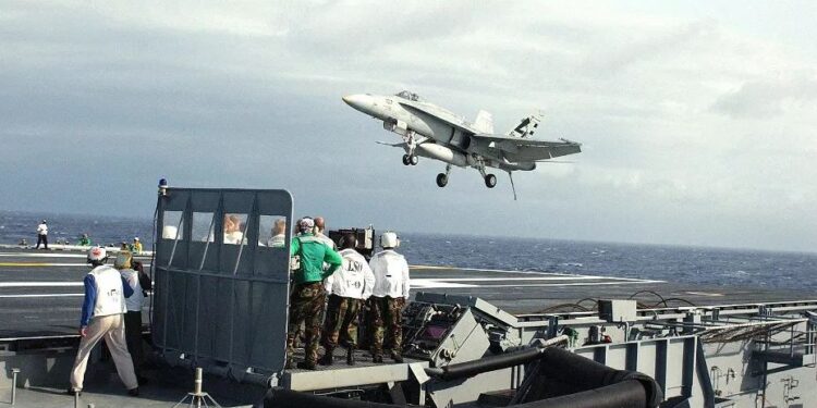 Un avión de combate despegando de la cubierta de un portaaviones.