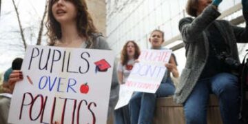 (LR) Eveline Straub, Kaitlyn Gang y Sonia Lerner, estudiantes de la Universidad George Washington, sostienen carteles junto a Julie Byrne durante la "Manos fuera de nuestras escuelas" manifestación frente al Departamento de Educación de EE. UU. el 4 de abril de 2025, en Washington, D/C. Estudiantes de la Universidad de Georgetown, la Universidad de Howard, la Universidad Americana, la Universidad George Washington, la Universidad George Mason y la Universidad de Temple se reunieron para protestar por el desmantelamiento del Departamento de Educación de Estados Unidos por parte del presidente Donald Trump.