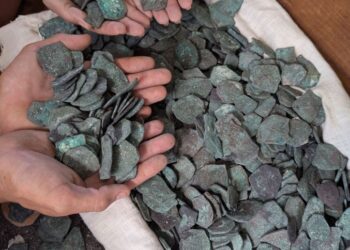 Las manos que sostienen monedas de oro y plata recuperadas del naufragio de la flota del tesoro de 1715.