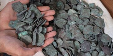 Las manos que sostienen monedas de oro y plata recuperadas del naufragio de la flota del tesoro de 1715.