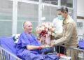 Vernon Unsworth, el salvador británico, recibe un ramo de flores en el hospital de manos de un funcionario tailandés.