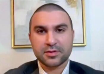 Un collage de imágenes que contiene 1 imagen. La imagen 1 muestra a Sami Hamdi, un hombre con la cabeza rapada y barba ligera, vestido con chaqueta y camisa con cuello.