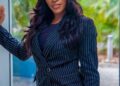 Sommie Maduagwu, una presentadora de televisión, de pie con un traje de rayas.