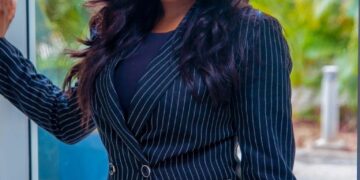 Sommie Maduagwu, una presentadora de televisión, de pie con un traje de rayas.