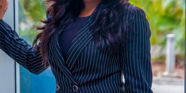 Sommie Maduagwu, una presentadora de televisión, de pie con un traje de rayas.