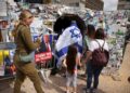 La gente visita la instalación de un túnel junto a un cartel de Donald Trump en "Plaza de los Rehenes" en Tel Aviv, Israel.