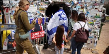 La gente visita la instalación de un túnel junto a un cartel de Donald Trump en "Plaza de los Rehenes" en Tel Aviv, Israel.