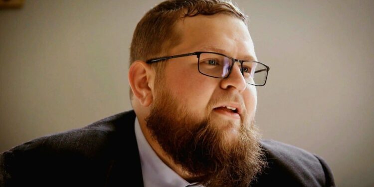 Un hombre con barba y gafas mirando hacia la derecha.