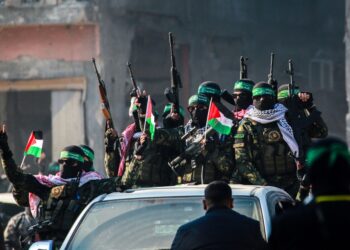 Militantes de Ha en un coche en Jabalia antes de un intercambio de rehenes, mostrando armas y banderas palestinas.