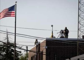 Una policía federal se encuentra junto a un rifle de francotirador en el techo de un centro de detención y procesamiento de inmigrantes durante una protesta el 3 de octubre de 2025 en Broadview, Illinois.