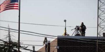 Una policía federal se encuentra junto a un rifle de francotirador en el techo de un centro de detención y procesamiento de inmigrantes durante una protesta el 3 de octubre de 2025 en Broadview, Illinois.