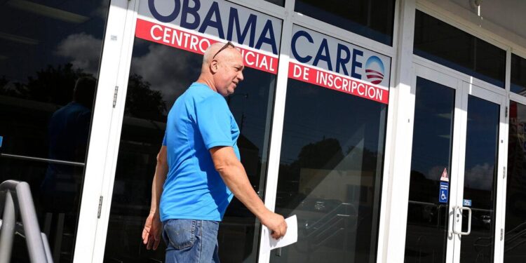 Un hombre cerca de una oficina con un cartel sobre Obamacare, o la Ley de Atención Médica Asequible, en Miami, Florida, en una fotografía de archivo sin fecha. (Joe Raedle/Getty Images)