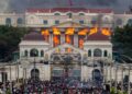 El fuego y el humo se elevan del Palacio Singha Durbar, que alberga edificios del gobierno y del Parlamento, a medida que los manifestantes se reúnen debajo durante las violentas manifestaciones en Katmandú.