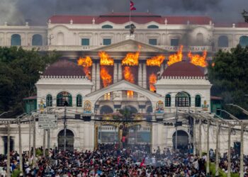 El fuego y el humo se elevan del Palacio Singha Durbar, que alberga edificios del gobierno y del Parlamento, a medida que los manifestantes se reúnen debajo durante las violentas manifestaciones en Katmandú.