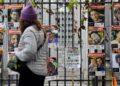 Una mujer pasa junto a una valla cubierta de carteles de rehenes israelíes, en su mayoría hombres, con las palabras "Tráelos a casa ahora" y "entführt" (secuestrado).