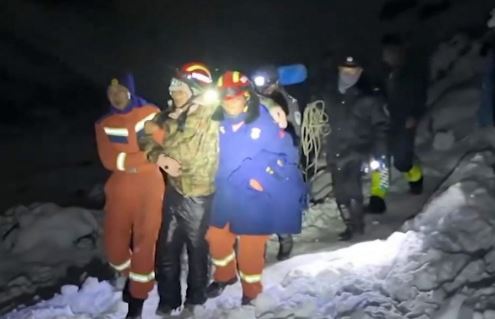 Los rescatadores en la nieve ayudan a un excursionista varado por la noche con faros.