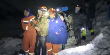 Los rescatadores en la nieve ayudan a un excursionista varado por la noche con faros.