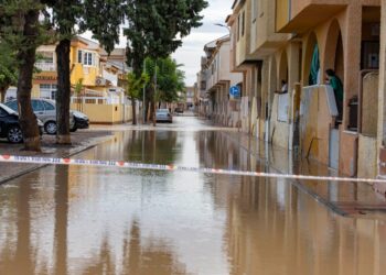 Una calle inundada en Los Alcázares, España, con un "POLICIA LOCAL" cinta de barrera extendida a través de él.