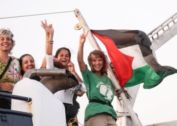 Greta Thunberg y un miembro de la tripulación flash de la victoria de su barco, con la bandera palestina volando.