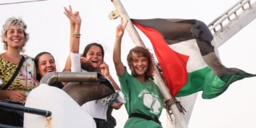 Greta Thunberg y un miembro de la tripulación flash de la victoria de su barco, con la bandera palestina volando.