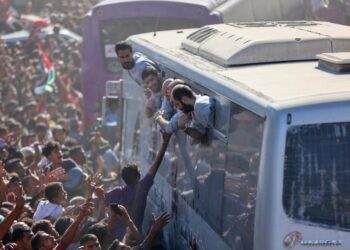 Palestinos liberados de prisiones israelíes se acercan desde las ventanillas de los autobuses a sus seguidores en Khan Yunis.