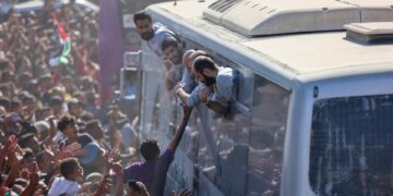 Palestinos liberados de prisiones israelíes se acercan desde las ventanillas de los autobuses a sus seguidores en Khan Yunis.