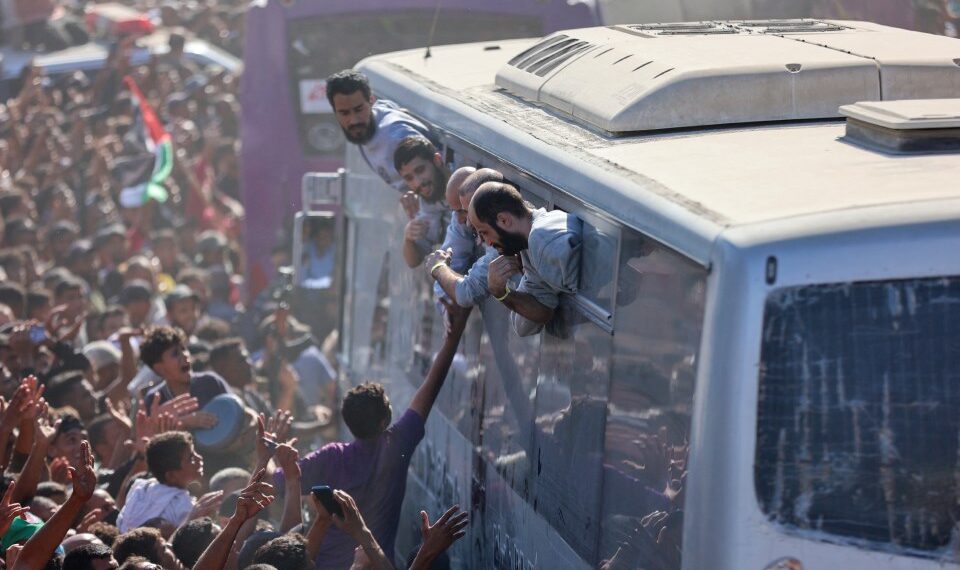 Palestinos liberados de prisiones israelíes se acercan desde las ventanillas de los autobuses a sus seguidores en Khan Yunis.