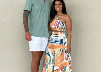 Mujer y hombre de pie juntos y sonriendo.