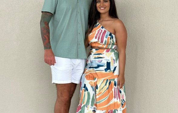 Mujer y hombre de pie juntos y sonriendo.