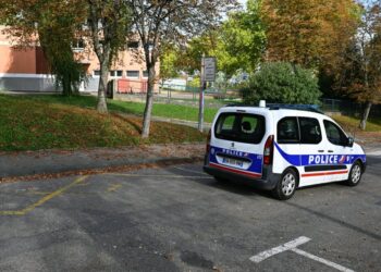 Un vehículo de la policía francesa pasa por la escuela primaria francesa Montagne en Sarreguemines, noreste de Francia, el 13 de octubre de 2025, tras el probable suicidio de un alumno de 9 años el 11 de octubre de 2025. Rosas blancas en las puertas de la escuela: Las emociones estaban en pleno apogeo el 13 de octubre de 2025, en Sarreguemines (Mosela) después del probable suicidio de Sara, de 9 años, que fue encontrada muerta en su casa con un suicidio nota. Antes de que comenzaran las clases, una docena de padres se reunieron frente a la escuela primaria de Montagne. Se reunieron para mostrar su "apoyo" para la familia del niño, sino también para expresar su "inquietud" y "enojo" tras esta tragedia que azotó a esta localidad de 20.000 habitantes situada no lejos de la frontera alemana. (Foto de Jean-Christophe VERHAEGEN/AFP) (Foto de JEAN-CHRISTOPHE VERHAEGEN/AFP vía Getty Images)