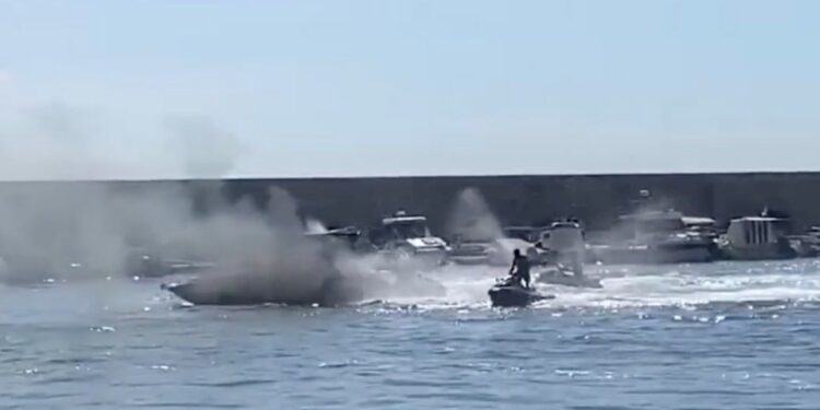 Una moto de agua ayuda a los bomberos a apagar un bote, creando un gran penacho de humo.
