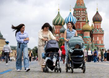 Tres mujeres empujando cochecitos para bebés en la Plaza Roja con la Catedral de San Basilio en el fondo.