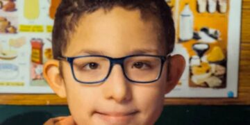 Un collage de imágenes que contiene 1 imagen. La imagen 1 muestra una foto de la cabeza de Rayan, un niño de 13 años con cabello oscuro y gafas azules, que lleva una sudadera con capucha naranja.