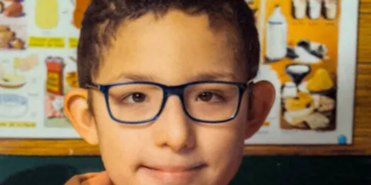 Un collage de imágenes que contiene 1 imagen. La imagen 1 muestra una foto de la cabeza de Rayan, un niño de 13 años con cabello oscuro y gafas azules, que lleva una sudadera con capucha naranja.