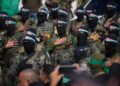 Los combatientes de Hamas en formación, con fatigas militares y balaclavas negros con diademas de bandera palestina.