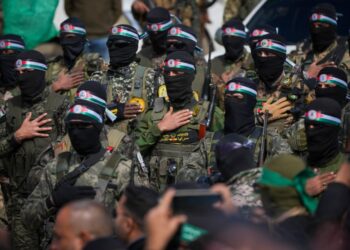 Los combatientes de Hamas en formación, con fatigas militares y balaclavas negros con diademas de bandera palestina.