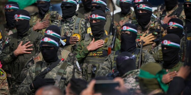 Los combatientes de Hamas en formación, con fatigas militares y balaclavas negros con diademas de bandera palestina.