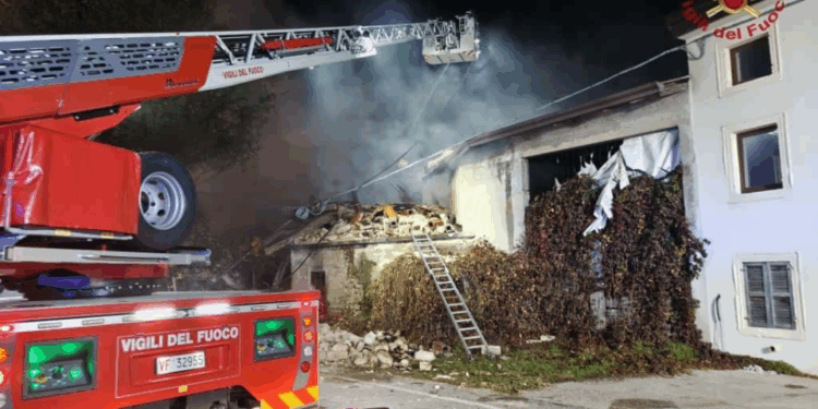 Bomberos trabajando de noche para extinguir un incendio en un edificio con el techo derrumbado.