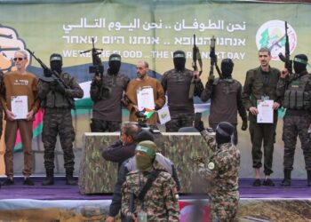 Ohad Ben Ami, Eli Sharabi, y / o Levy, con certificados, escoltados por los combatientes de Hamas en un escenario en Deir El-Balah, Central Gaza.