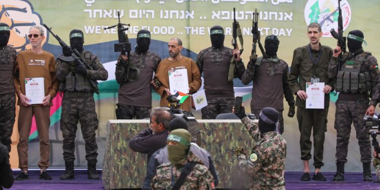 Ohad Ben Ami, Eli Sharabi, y / o Levy, con certificados, escoltados por los combatientes de Hamas en un escenario en Deir El-Balah, Central Gaza.
