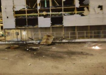 Edificio de fábrica dañado con humo en el fondo.