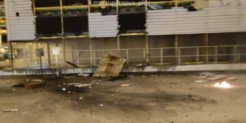 Edificio de fábrica dañado con humo en el fondo.