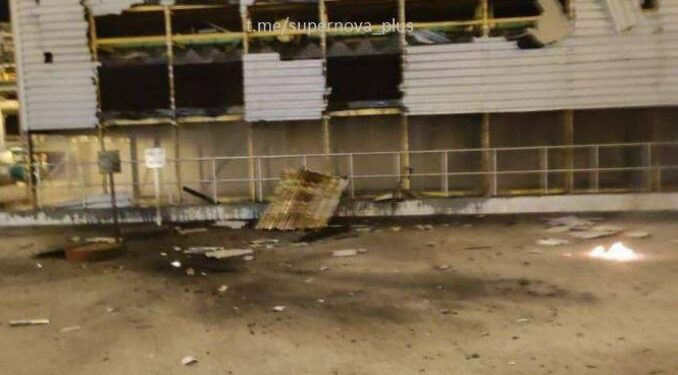 Edificio de fábrica dañado con humo en el fondo.