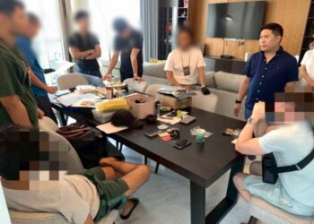 Personal policial y sospechosos se reúnen alrededor de una mesa con presuntos paquetes de droga.